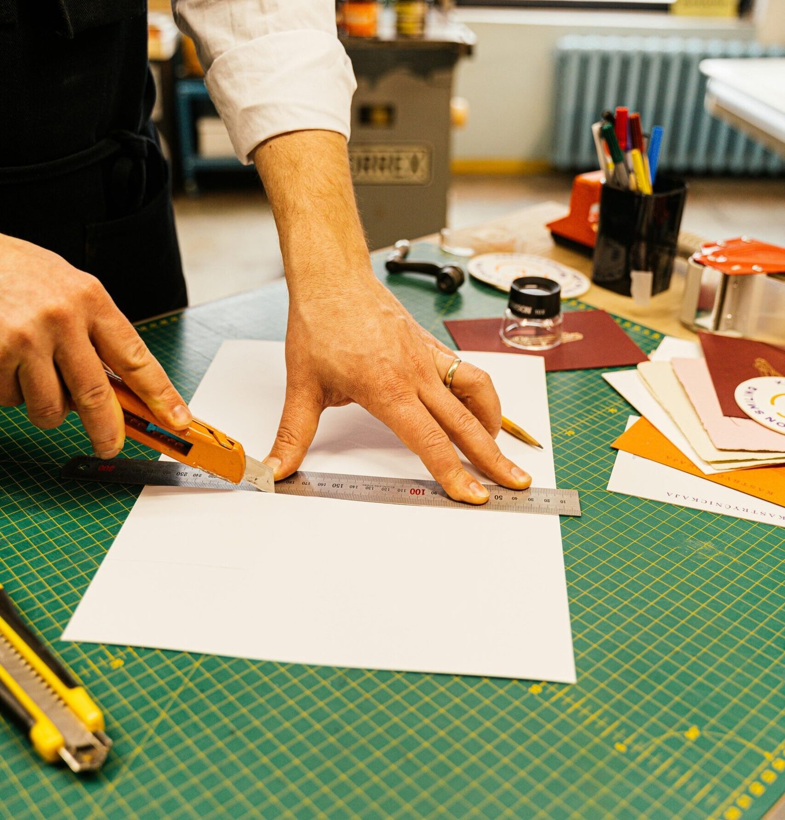 Close-up of hands cutting paper with precision tools in a creative workshop.